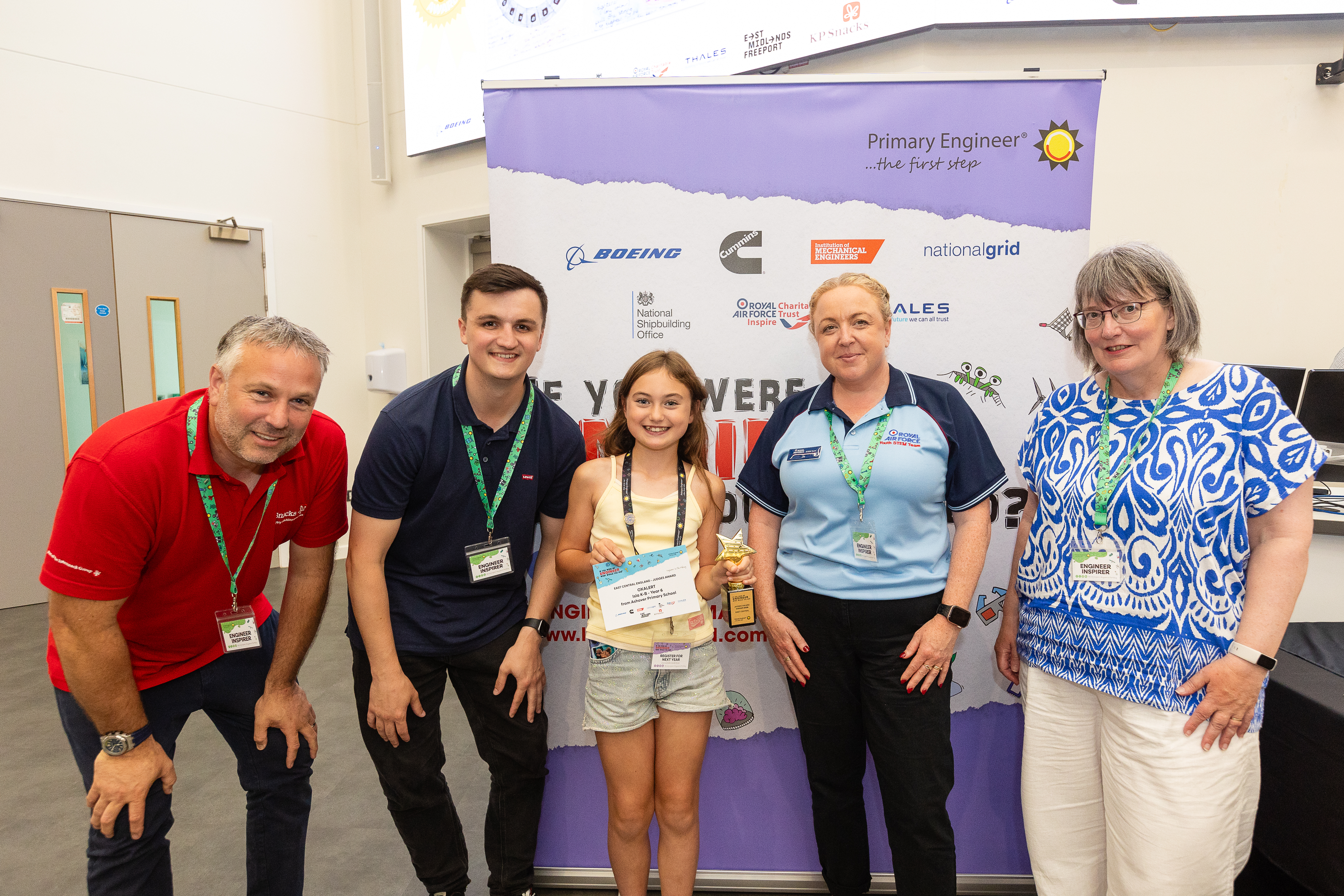 A group of adults stand with a young person in the middle holding a certificate