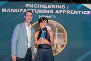 An image of two people standing on a stage, one presenting the other with an award